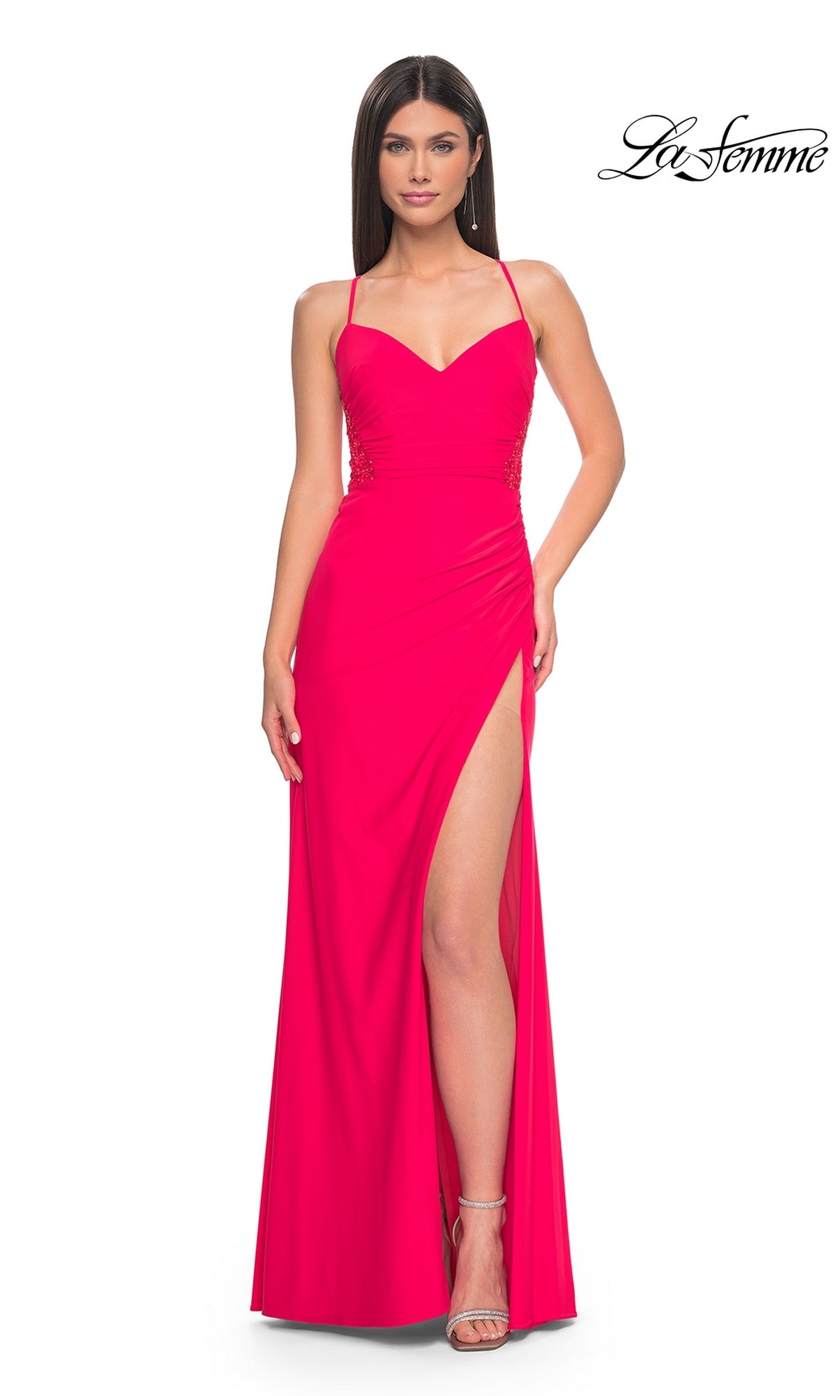 A woman in a La Femme Bright Hot Coral Long Prom Dress 31440 with spaghetti straps and a high side slit stands against a plain white background. The La Femme logo is displayed in the top right corner.
